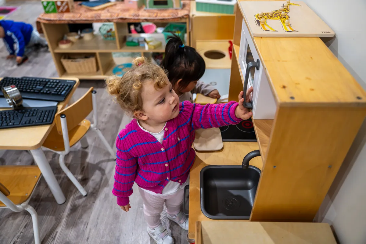 Two toddlers at the wooden play kitchen in the Tiny Tigers room, Little Jungle Dundas